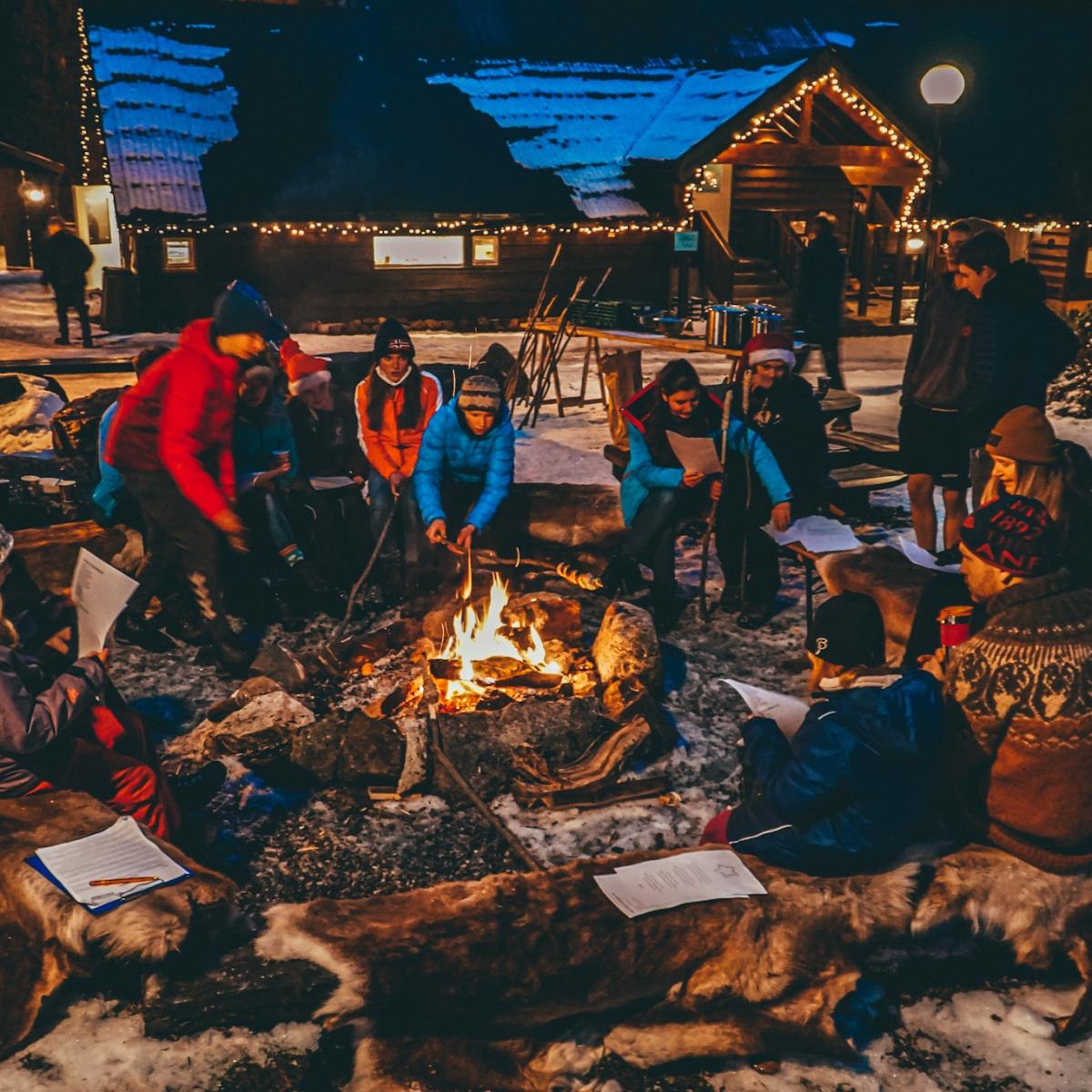 a group of people sitting at a crowded campfire