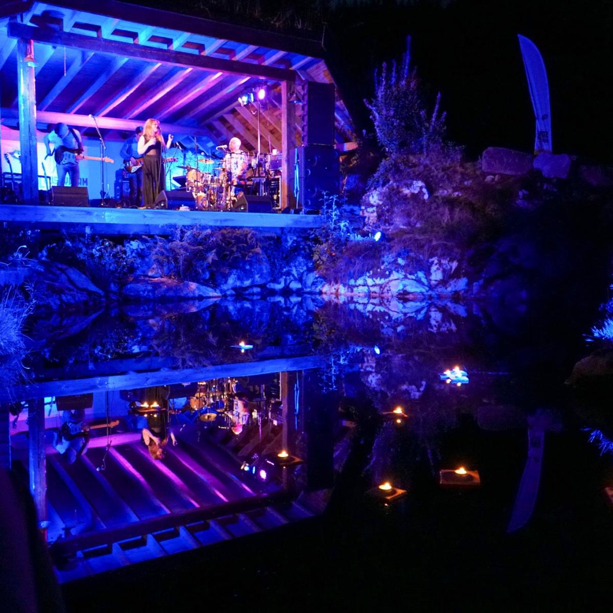 a band singing on a stage in front of a body of water