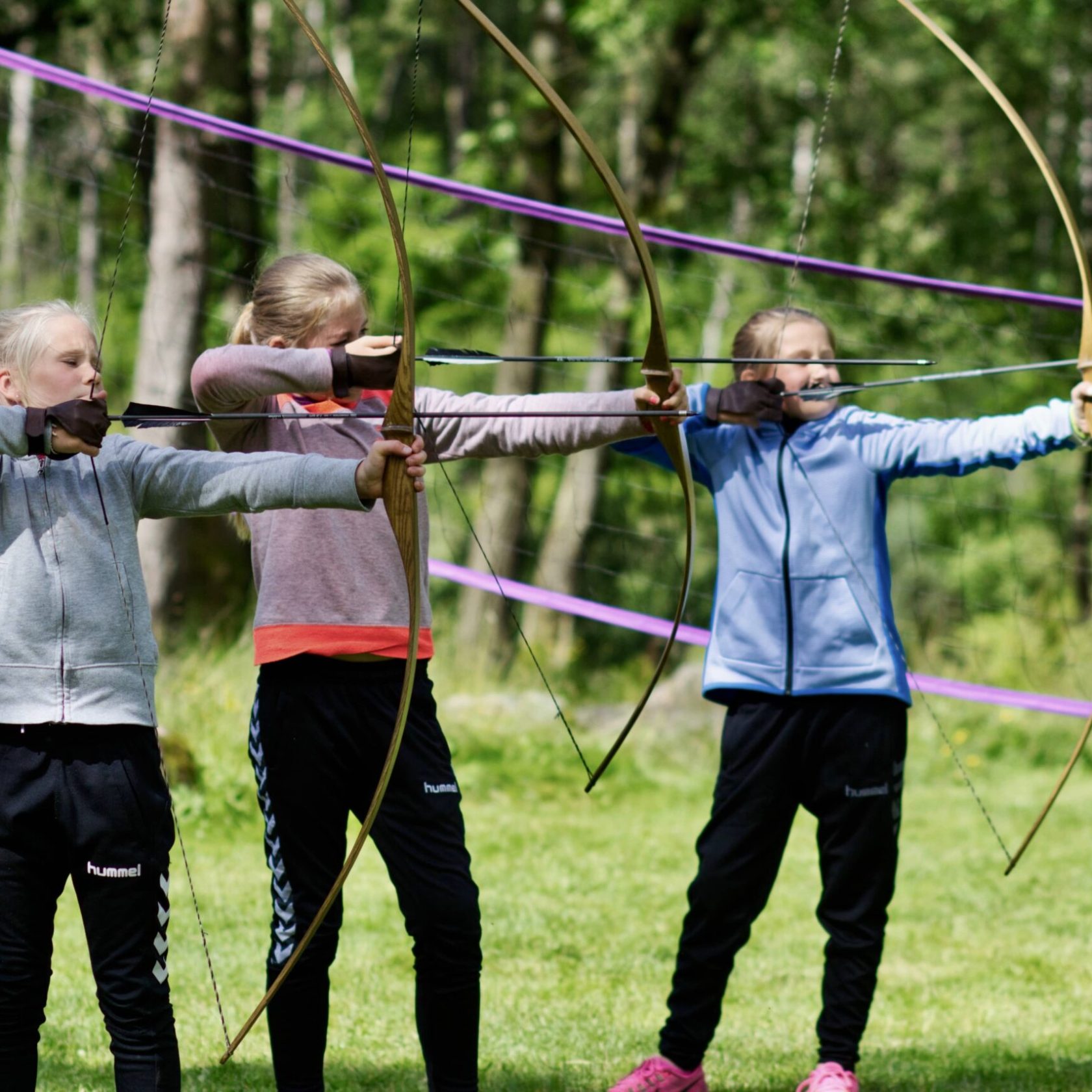 three girls shooting an arrow from a bow