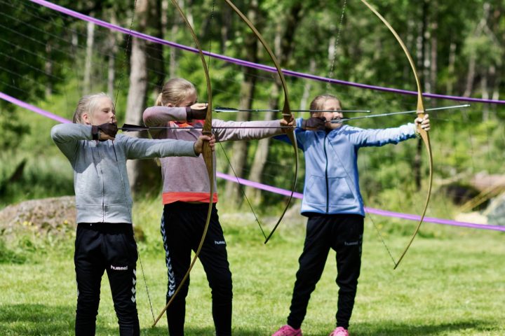 three girls shooting an arrow from a bow