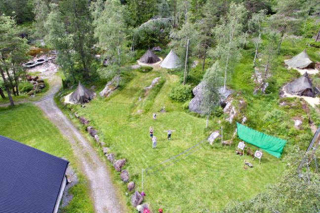 Aerial view of people on grass near tents and trees.