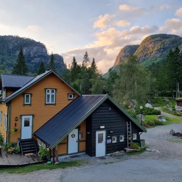 Charming wooden house in mountains with trees and cloudy sky.