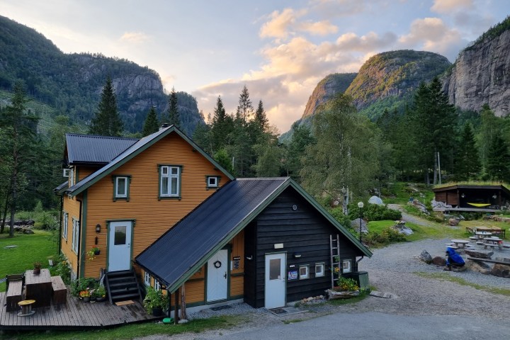 Charming wooden house in mountains with trees and cloudy sky.